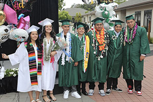 Happy graduates in caps and gowns, with balloons