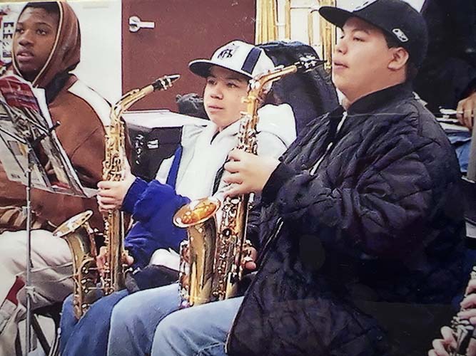Three boys playing saxophones in the band