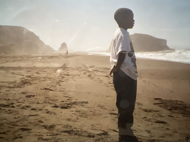 Boy at the beach looking at the water