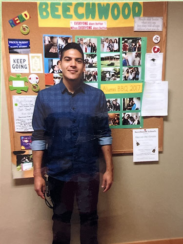 Man alum standing in front of Beechwood bulletin board